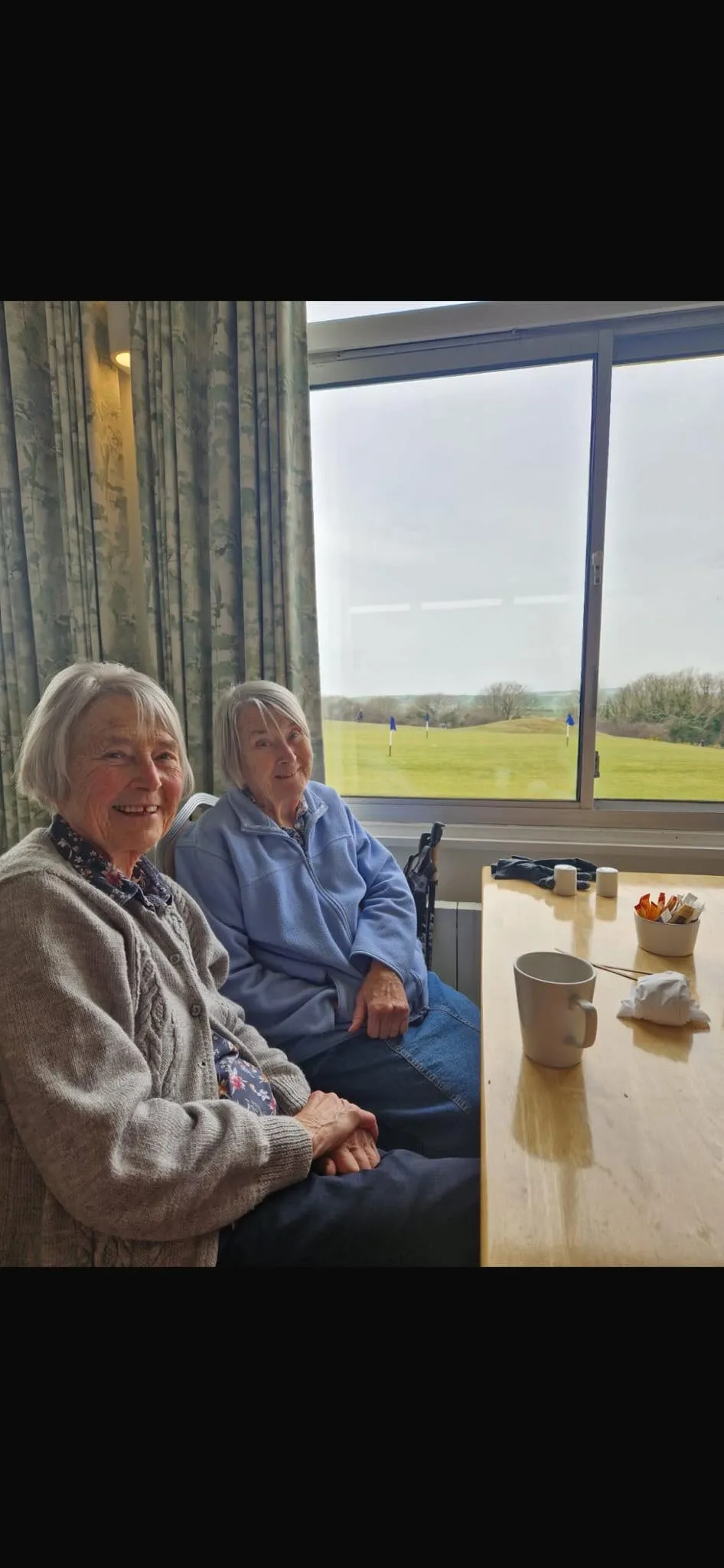 Two clients sitting together by a window with a cup of tea